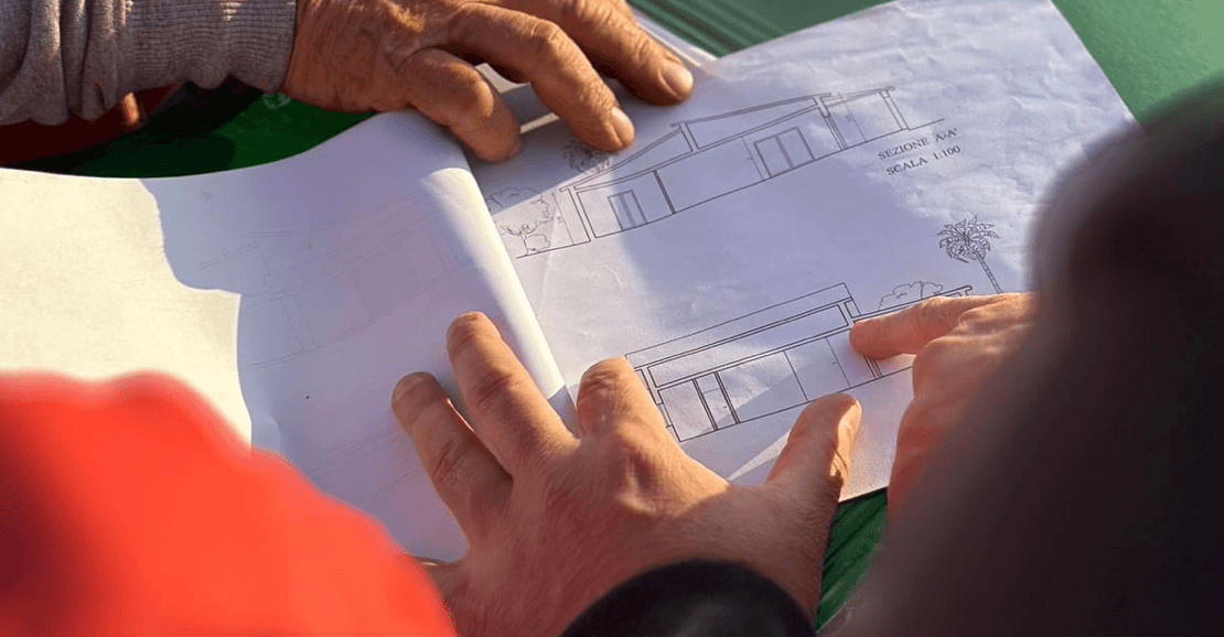 Architects reviewing construction blueprints together outdoors on site