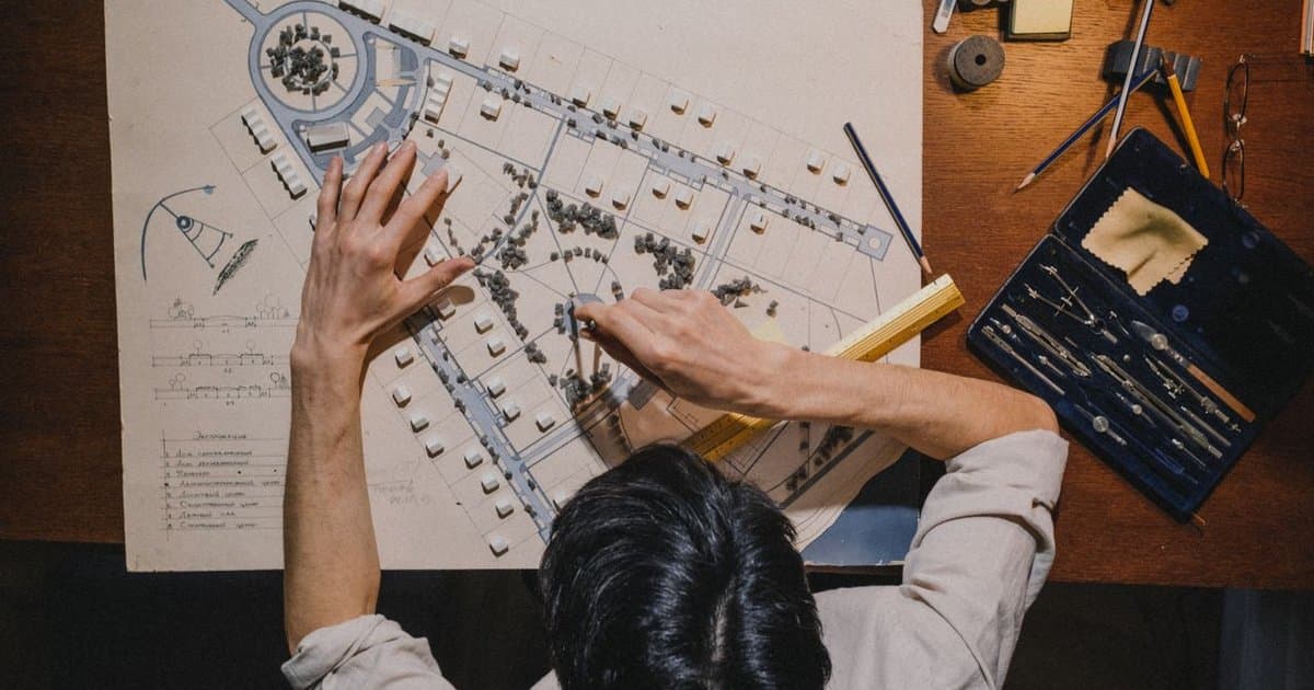 Architect working on a hand-drawn site master plan with drafting tools